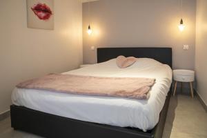 uma cama com lençóis brancos e um cobertor rosa em Chablis Spa 1er Cru Balnéo em Chablis