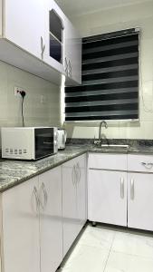 a kitchen with white cabinets and a microwave at Blueocean.cog in Benin City