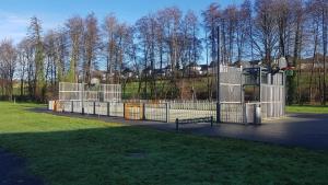 un parque con parque infantil con puerta y césped en Le Genest St Isles, en Le Genest