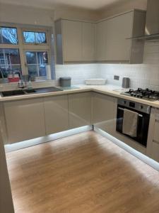 a kitchen with white cabinets and a wooden floor at Clarke's AirBnB in Worthing