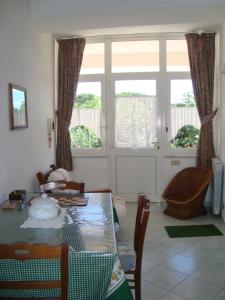 ein Wohnzimmer mit einem Tisch, Stühlen und Fenstern in der Unterkunft Villa Leonardo in Ischia