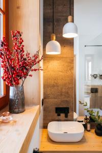 uma casa de banho com um lavatório e um vaso com flores vermelhas em White Sheep by LoftAffair em Kościelisko