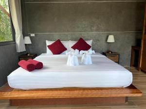 Vasinee Villa في ثونغ نايبان ياي: سرير كبير عليه وسائد حمراء وبيضاء