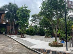 Vasinee Villa في ثونغ نايبان ياي: حديقة فيها اشجار ومبنى وشارع