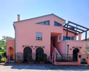 ein rosa Haus mit einem Zaun auf einem Parkplatz in der Unterkunft La Chiocciola Apartments in Santarcangelo di Romagna