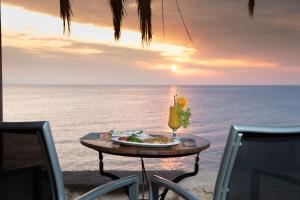 stół z talerzem jedzenia i drinka na plaży w obiekcie Τraditional seaside room HOMER w mieście Artemida