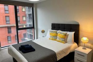 a bedroom with a bed with a large window at Fab 1 Bed Apartment with Balcony and River Views Sleeps 2 in Manchester