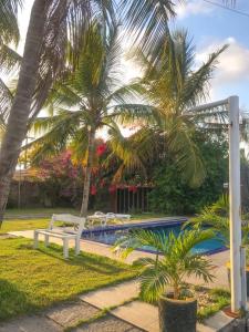 a pool with two palm trees and a white bench at Espaço Billynghan in Barreirinhas