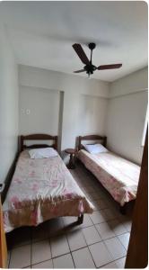 - une chambre avec 2 lits et un ventilateur de plafond dans l'établissement Condomínio Juacema, à Cabo Frio