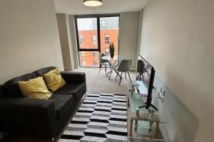 a living room with a black couch and a table at Large 1 Bed Apt in Central Manchester Sleeps 2 in Manchester