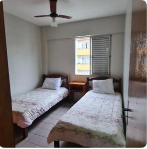 2 Betten in einem Zimmer mit Deckenventilator in der Unterkunft Condomínio Juacema in Cabo Frio