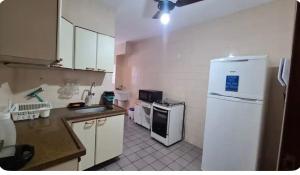 Il comprend une cuisine équipée d'un réfrigérateur blanc et d'une cuisinière. dans l'établissement Condomínio Juacema, à Cabo Frio