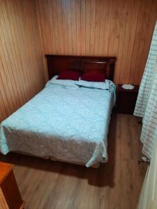 ein Schlafzimmer mit einem Bett mit zwei roten Kissen in der Unterkunft Casa Bellavista Full Equipada in Tomé
