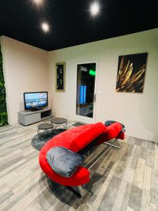 a living room with a red couch and a television at L'appar-T loft avec Spa privatif et jardin in Gières