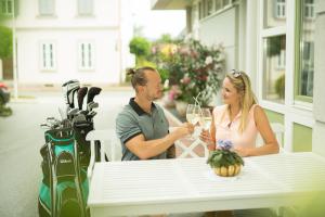 Un uomo e una donna seduti a un tavolo con un bicchiere di vino di Garni Hotel Danja Herold e. U. a Maria Lankowitz