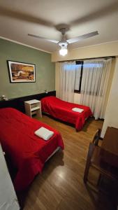 a room with two beds and a table in it at Hotel Cosmos in Mar del Plata