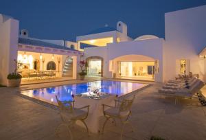 Villa Santorini في فيلانكولوس: منزل مع مسبح وكراسي وطاولة
