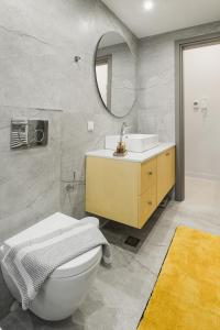 bagno con lavandino, servizi igienici e specchio di Singer Suites Kalamata - Luxury Suites a Kalamáta
