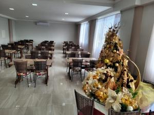 a christmas tree in a room with tables and chairs at Hotel Rio Paraná in Guaíra