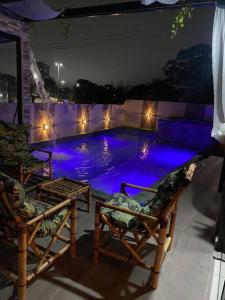 uma piscina à noite com duas cadeiras e luzes em Alugo espaço com piscina + Jacuzzi! em Mogi das Cruzes