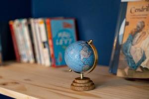 Un petit globe assis sur une étagère à côté des livres dans l'établissement Maisonnette & Jacuzzi, à Saint-Valery-sur-Somme