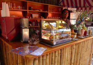 un hombre está parado detrás de un mostrador en una panadería en The Octopus's Garden Hostel, en Cruz de Huanacaxtle