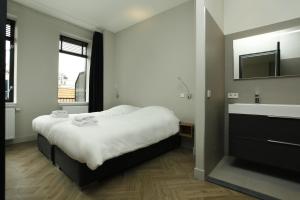 a bedroom with a large bed and a sink at Stayci Serviced Apartments Westeinde in The Hague
