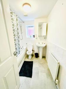 a white bathroom with a toilet and a sink at 3 Bedroom Affordable Family Detached House - Business Contractors, Midlands Location - Private garden,Free car park,TV- Netflix and Free WiFi in Coventry