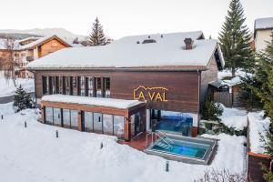 une maison avec une piscine dans la neige dans l'établissement La Val Hotel & Spa, à Brigels