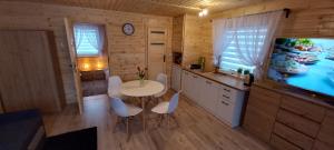 een keuken met een tafel en stoelen en een televisie bij Grabska Osada SUN HOUSE - domki całoroczne ogrzewane in Grabce