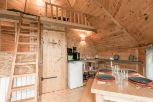 una cucina con pareti in legno, tavolo e frigorifero di KOTA a Daumeray
