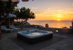 a hot tub on a patio with a sunset in the background at Villa Titina - Sunset Apartments in Ischia