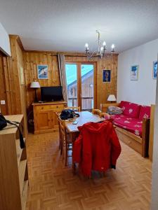 a living room with a table and a red couch at Appartement dans un chalet, résidence avec piscine in La Toussuire