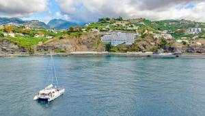 a boat floating in a body of water with a mountain at Hotel Orca Praia - Adults Only in Funchal
