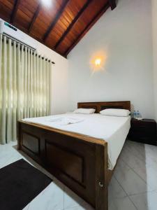 - une chambre avec un grand lit et un cadre en bois dans l'établissement Langama Thena - ළඟම තැන, à Anurâdhapura