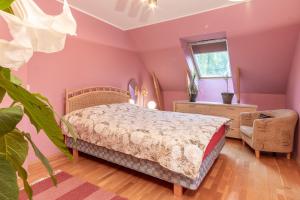 um quarto com paredes cor-de-rosa, uma cama e uma cadeira. em HermiinStay - apartment with sauna and hot tub em Tartu