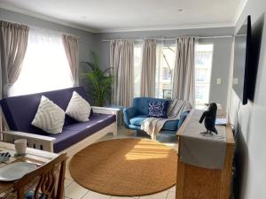sala de estar con sofá azul y mesa en Ocean Escape, en Strand