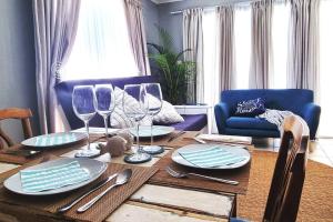 mesa de comedor con copas de vino y sofá azul en Ocean Escape, en Strand