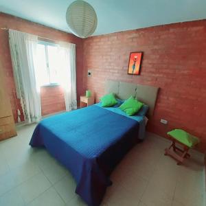 een slaapkamer met een blauw bed en een bakstenen muur bij CASA HOST Las Grutas in Las Grutas