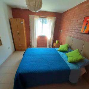 een slaapkamer met een blauw bed met groene kussens bij CASA HOST Las Grutas in Las Grutas