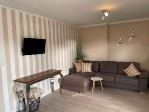 a living room with a couch and a tv at Die lütte Welle Grömitz in Grömitz