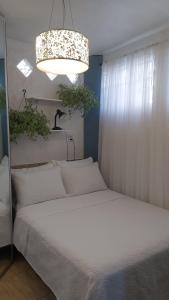 フロリアノポリスにあるCasa na praia do Campecheのベッドルーム(白いベッド1台、シャンデリア付)