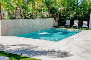 una piscina con 2 sillas y una fuente en Villa JAP, en Benidorm