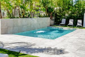 een zwembad met 2 stoelen en een fontein bij Villa JAP in Benidorm