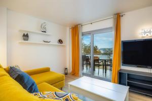 sala de estar con sofá amarillo y TV en Apartamento Olga, en Cala Millor