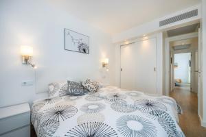 Dormitorio blanco con cama con edredón en Apartamento Olga, en Cala Millor