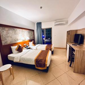a hotel room with two beds and a television at Aquavista Hotel & Suites in Aqaba