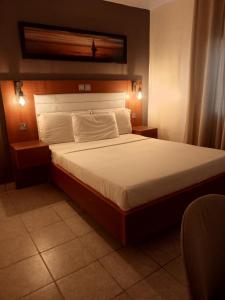 - une chambre avec un grand lit et des draps blancs dans l'établissement First International Inn Downtown, à Limbe