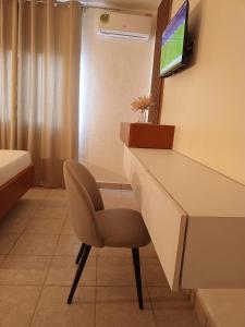 a room with a desk and a chair and a tv at First International Inn Downtown in Limbe