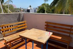 2 houten banken en een houten tafel op een balkon bij The Octopus's Garden Hostel in Cruz de Huanacaxtle